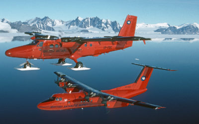 Two red aeroplanes flying above the sea