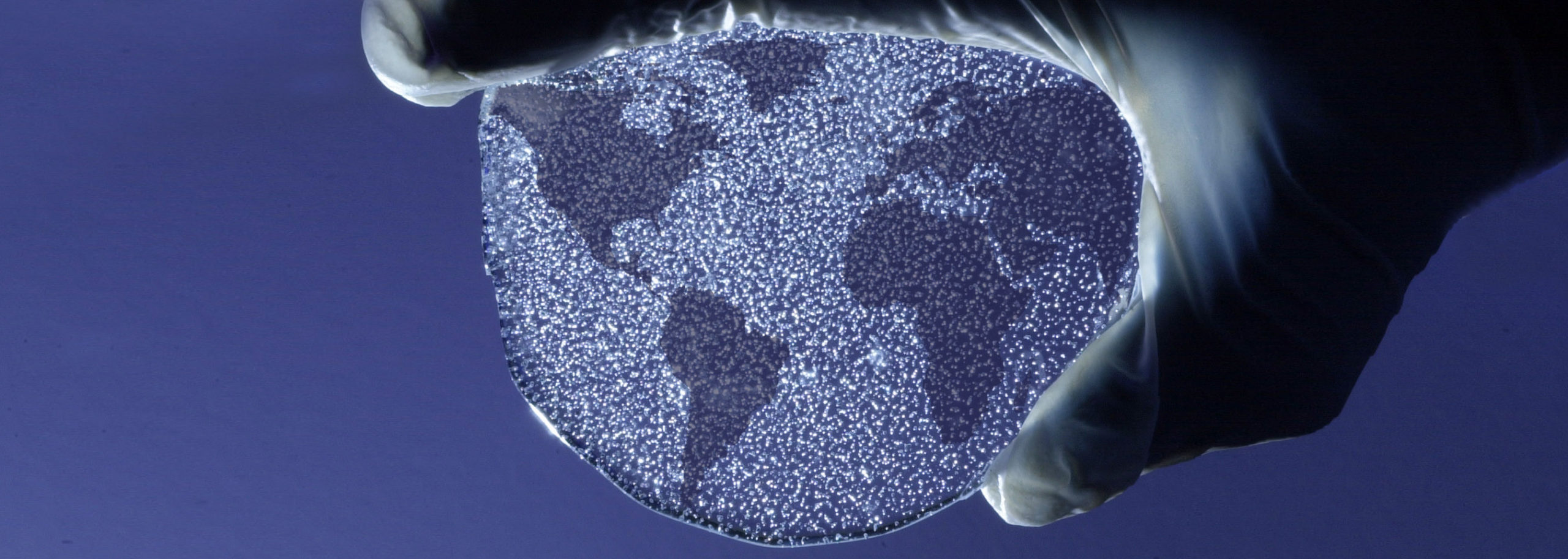 Earth's continents drawn onto a circle of ice held by hand from above