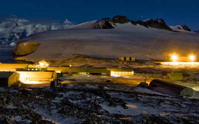 A research base lit up in an icy landscape in the dark