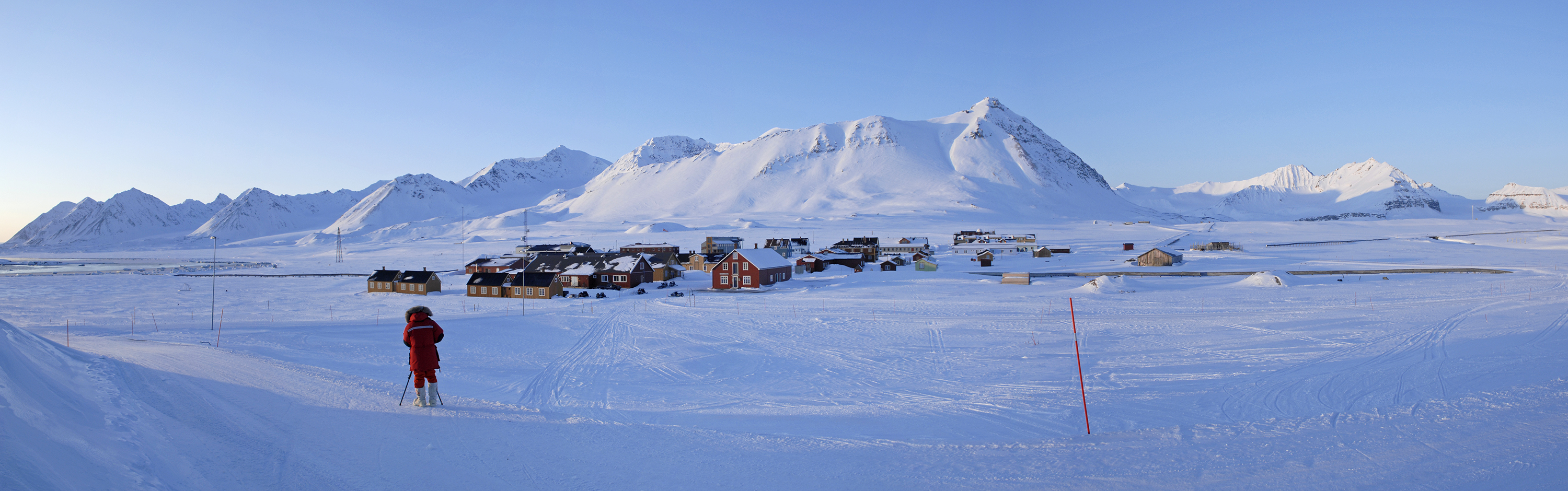 A person in the foreground filming a distant research station