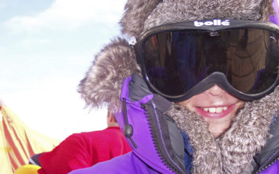 A person wearing winter clothing and goggles looking into the camera