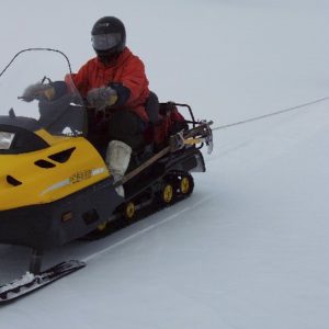 Two-person skidoo team roped together for safe field travel.