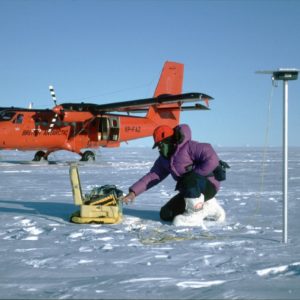 A glaciologist uses Twin Otter aircraft and GPS to survey the flow of the ice sheet. The pole on which the antenna is mounted will be re-visited. Measuring the speed of ice-flow allows glaciologists calculate whether the ice sheet is changing. Here a glaciologist uses a Global Positioning System receiver to measure the position of an alumimium pole planted in the snow. Remeasurement of its position after a year's movement will allow the ice-flow speed to be determined. The measurement only takes one hour, so it can be efficiently supported by aircraft.