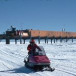 A person riding a skidoo down a snow covered slope.