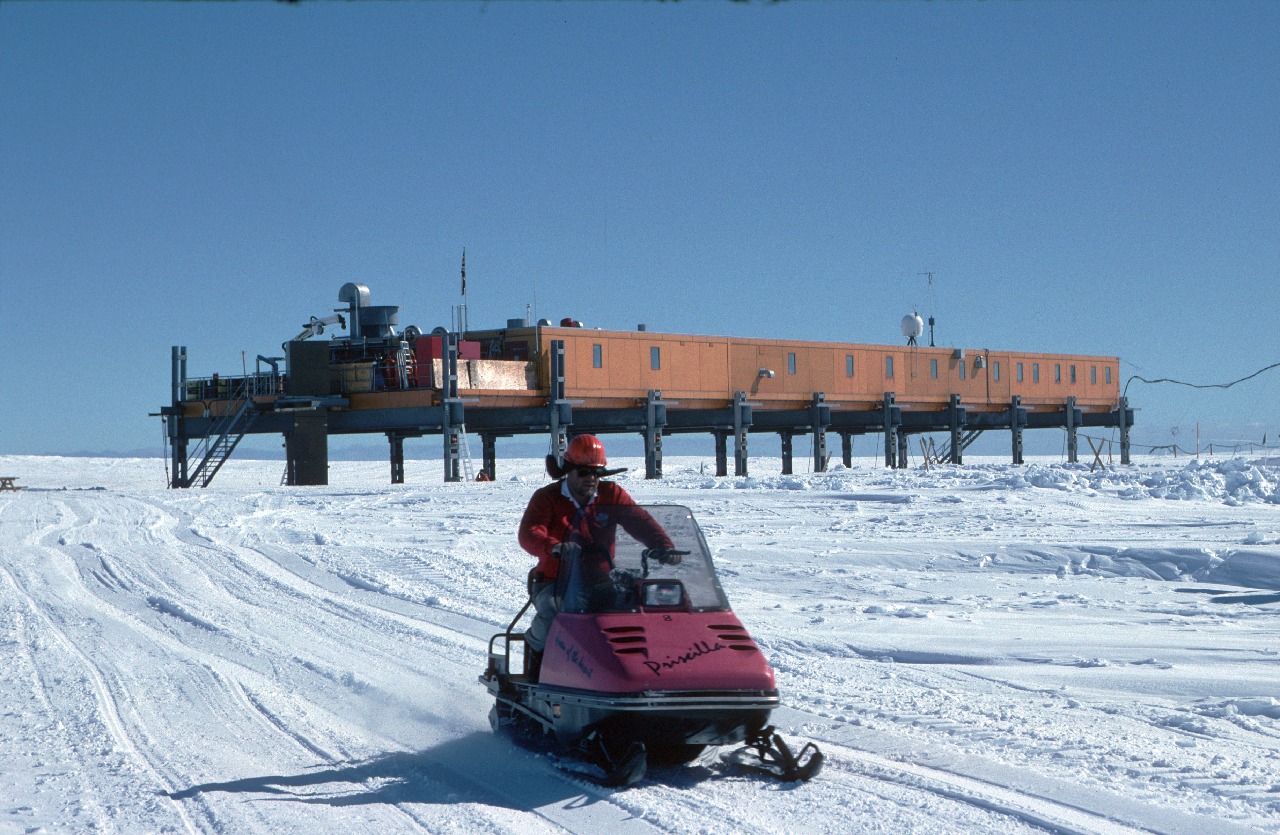 A person riding a skidoo down a snow covered slope.
