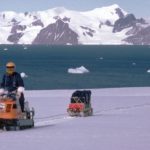 A man riding a skidoo down a snow covered mountain.