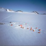 A group of people flying kites in a body of water.
