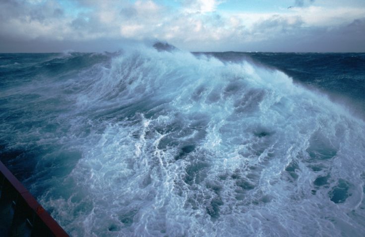 A man riding a wave on top of a body of water.