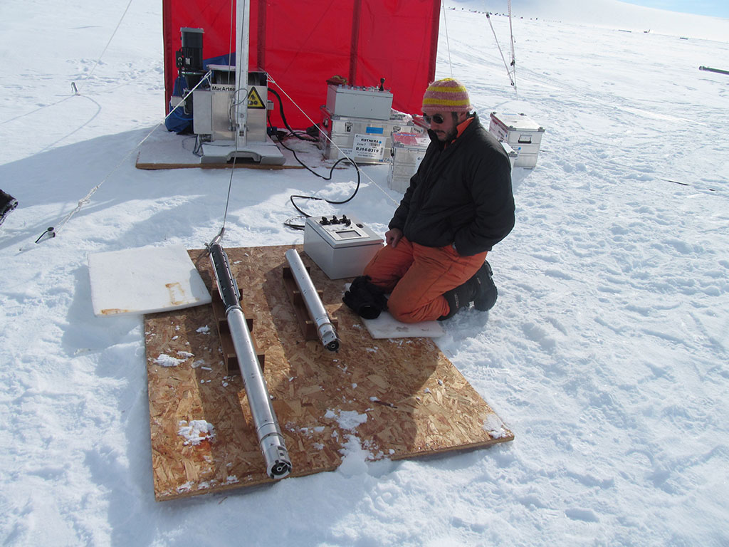 A person sitting on top of a snow covered slope.
