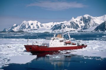 A large ship in the water with a mountain in the snow.