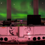A green aurora out of the windows of a research station