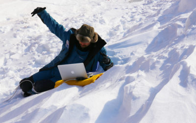 A person lying on top of a snow covered slope.