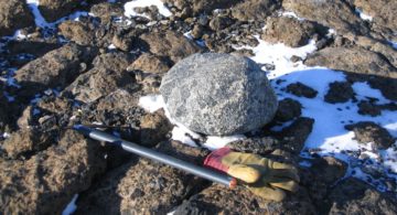 A pile of snow next to a rock.