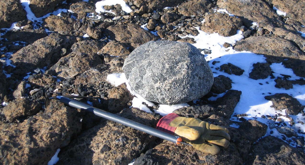 A pile of snow next to a rock.