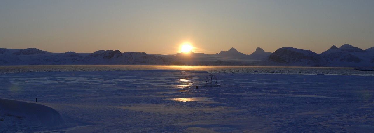 A sunset over a body of water with a mountain in the background.
