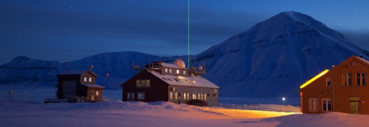 The Koldewey Station at Ny Alesund on Svalbard, is run by the German Alfred Wegener Institute (AWI for the observation of the north polar stratosphere. A variety of optical instruments are installed on and operated from the roof of this building. An infrared spectrometer measures type and quantity of trace gases in the troposphere and stratosphere. A photometer which uses the sun and the moon as light sources measures the optical depth of atmospheric aerosols throughout the year. The concentration of ozone and aerosols in the atmosphere is determined by means of a so-called LIDAR (laser-â€˜radarâ€™) seen here clearly above the station. In addition, from the bulding to the left, balloon-borne sensors record temperature, humidity and air pressure, as well as ozone-profiles.