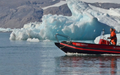 A small boat in a body of water with a mountain in the background.