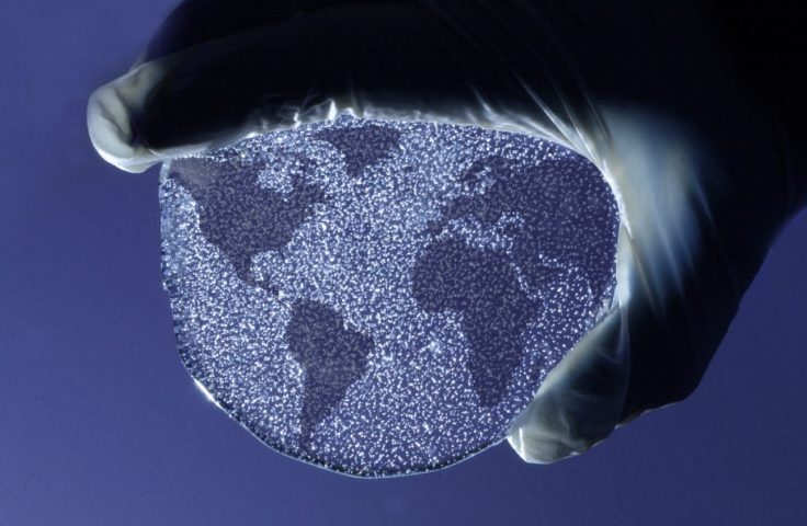 Scientist's hand holding a slice of ice core from Dyer Plateaux, depth 230m, with the globe superimposed on top of it. Trapped air bubbles, an archive of past atmosphere, are visible in the ice.