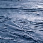 A plane flying over a body of water.
