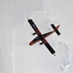 A plane flying through the air above an icy landscape
