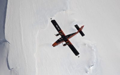 A plane flying through the air above an icy landscape