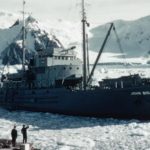 A large ship in the water with a mountain in the snow.