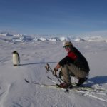 A man next to a penguin in a snowy landscape