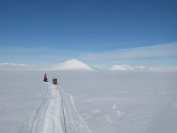 A person riding a snowboard down a snow covered slope.