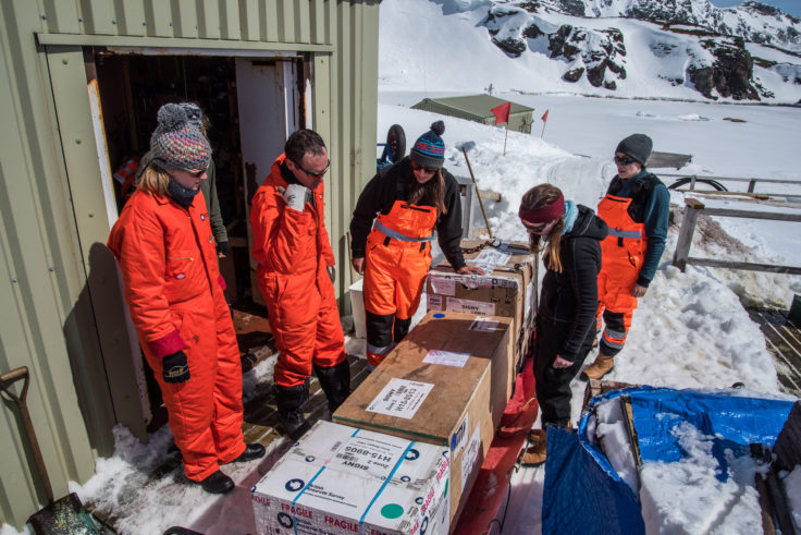 Staff prepare to unload a sledge of cargo ski-doo'd up from shore to the Top Store