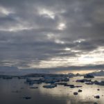 A group of clouds in the sky over a body of water.