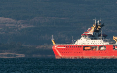 A large ship in a body of water with a mountain in the background