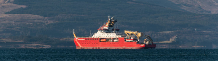 A large ship in a body of water with a mountain in the background