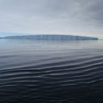 A large body of water in front of ice shelf