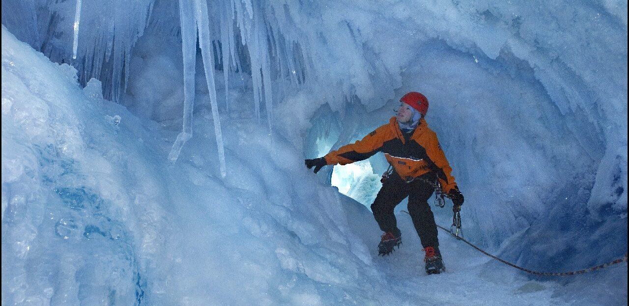 A man riding a snowboard down a snow covered slope.
