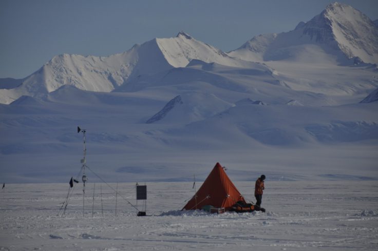 A person standing on top of a snow covered mountain.