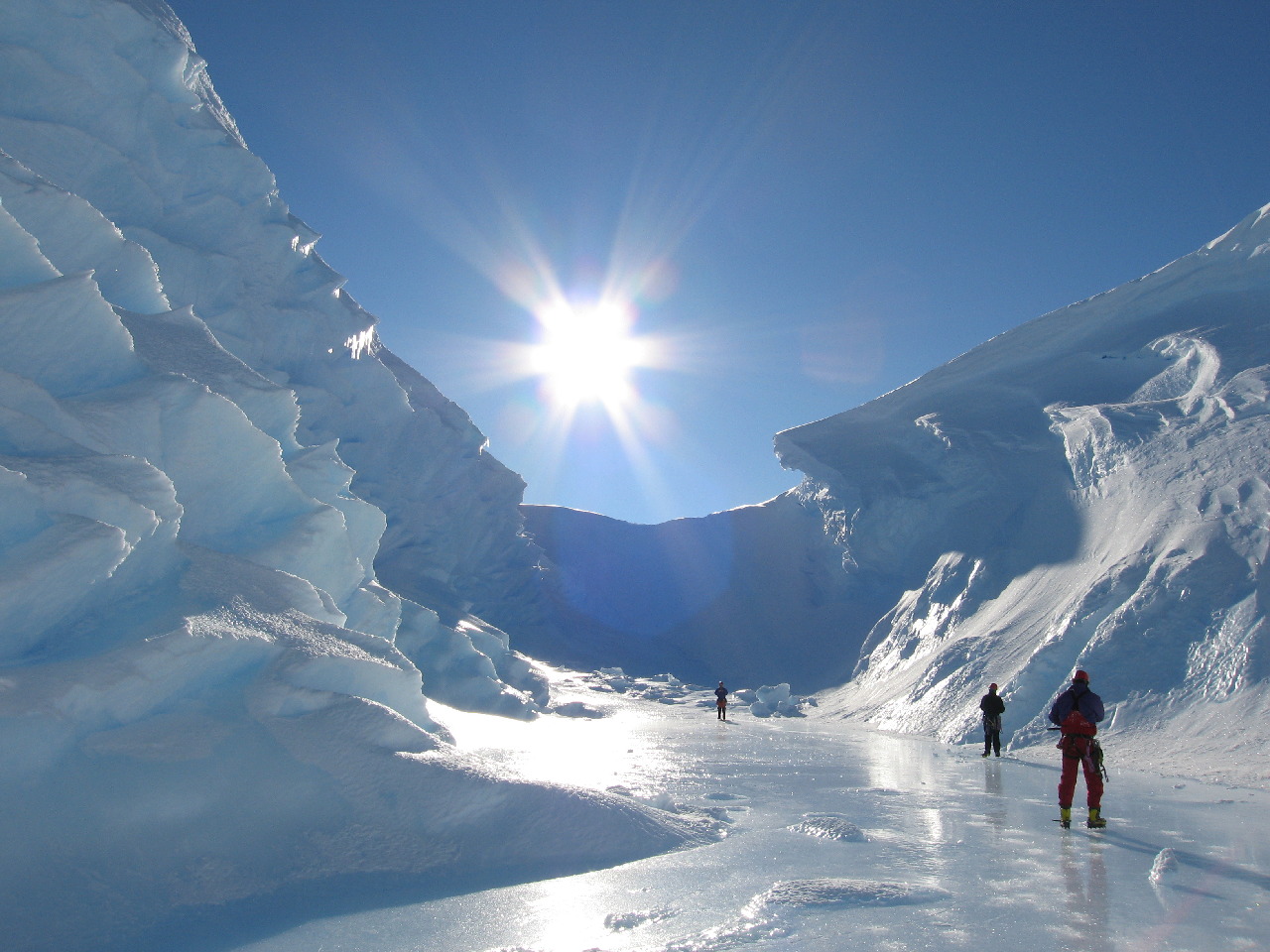 A group of people standing at the bottom of a valley of ice