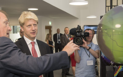Jo johnson wearing a suit and tie holding a cell phone.
