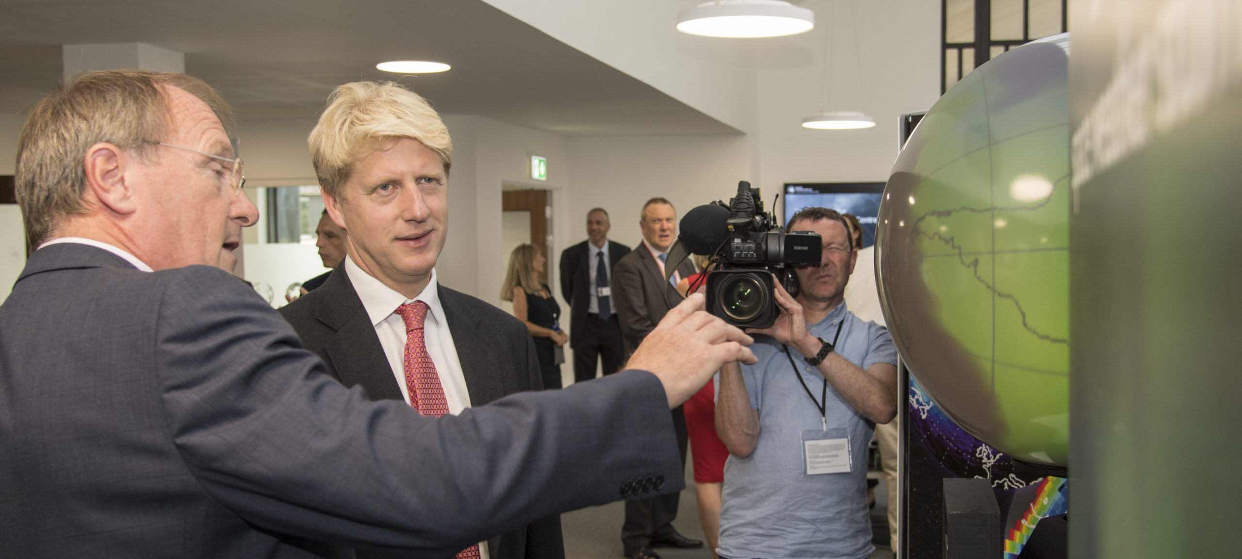 Jo johnson wearing a suit and tie holding a cell phone.