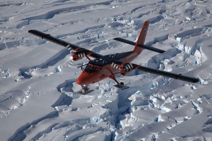 A aeroplace flying over a snowy landscape