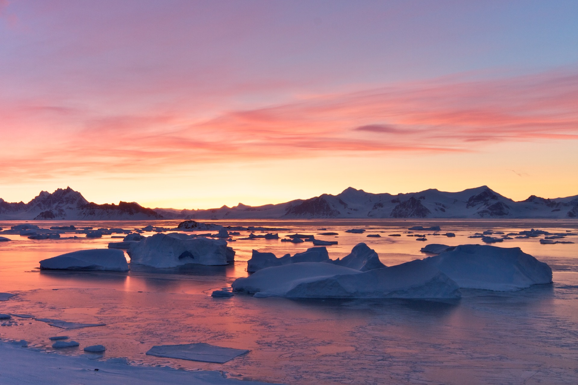 A sunset over a body of water with a mountain in the background.
