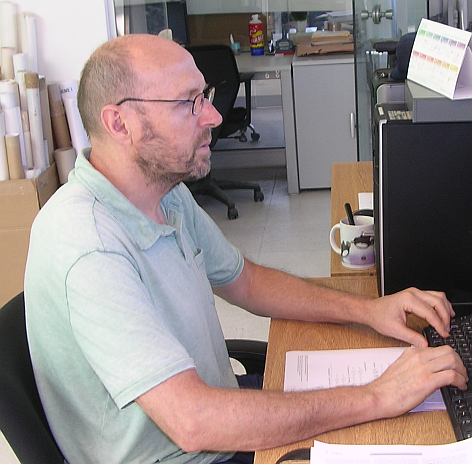 A man sitting at a table using a laptop.