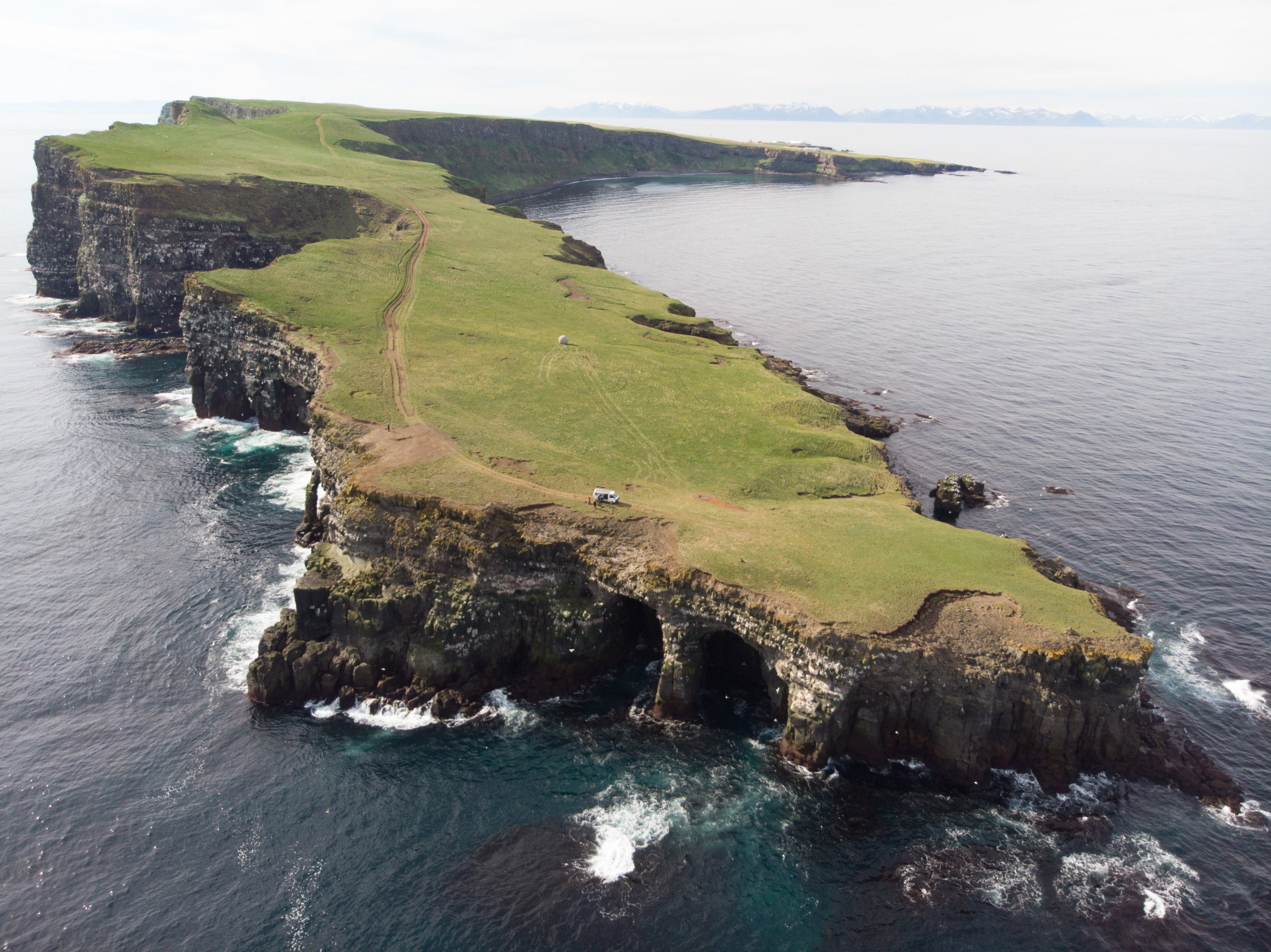 A close up of a hillside next to a body of water with old head of kinsale in the background.
