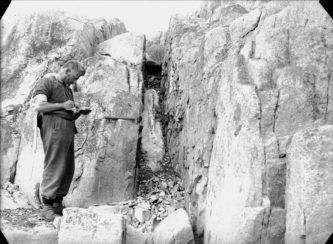 A man standing next to a rock wall.