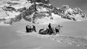 A group of people riding on the back of a horse in the snow.