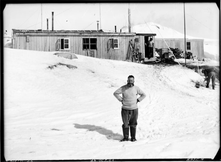 Lewis ‘Chippy’ Ashton standing in front of the recently completed Bransfield House, Port Lockroy, 26th October 1944. Photographer: I M Lamb. Archive ref: AD6/19/1/A52