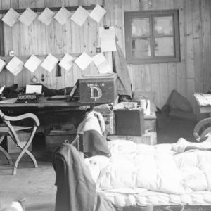 An old photo of a living room filled with furniture and a bed.