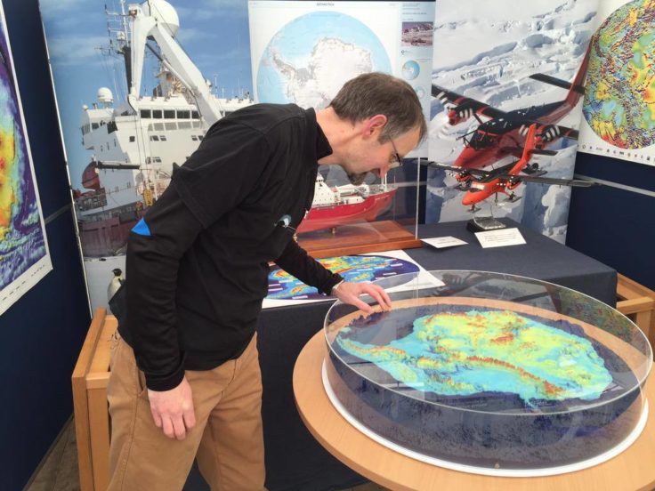 A person inspecting a model of Antarctica