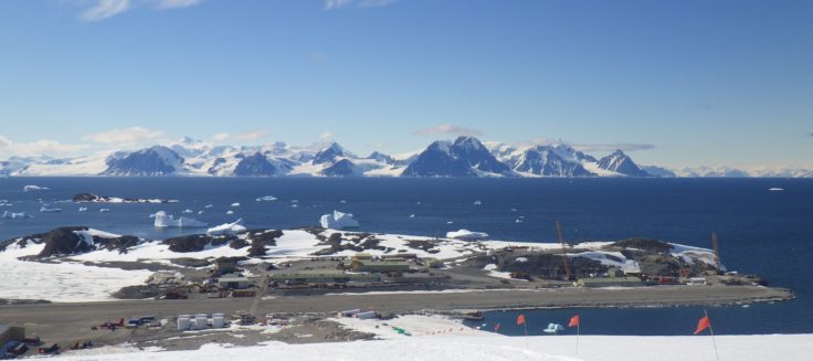 A group of people on a beach with a mountain in the background.