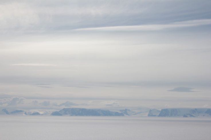 A group of clouds in the sky over a body of water.