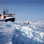 A large boat in the sea ice with people in the foreground